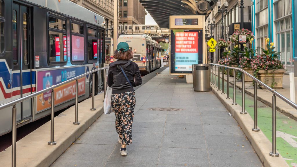 A woman walks towards a DOOH ad at a bus stop