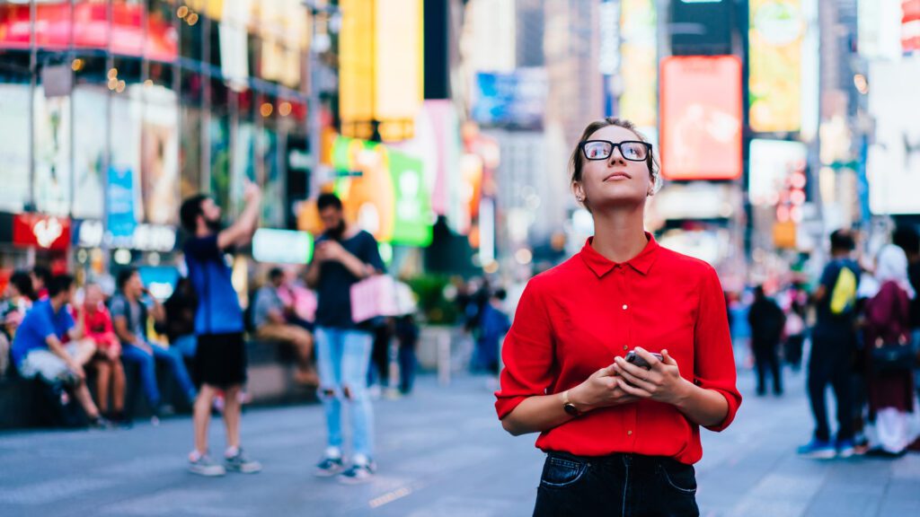 A woman observes many digital out of home ads in Times Square, NY.