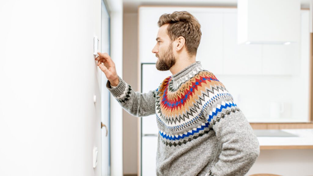 A man struggles with his thermostat