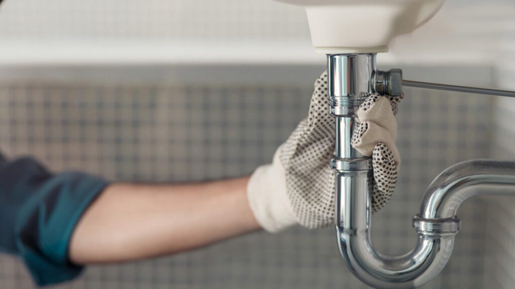 A home services professional works on plumbing